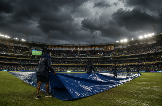 Ground staff cover the pitch before a rain-threatened IPL night match.