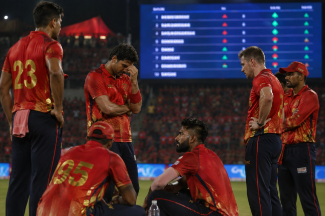 Generic Punjab Kings-style cricketers react during a difficult IPL 2026 playoff race moment.